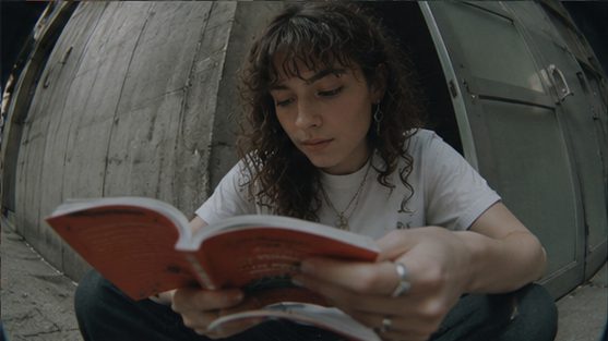 A person reads outdoors against a city wall