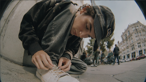 A person ties a shoelace on a city street